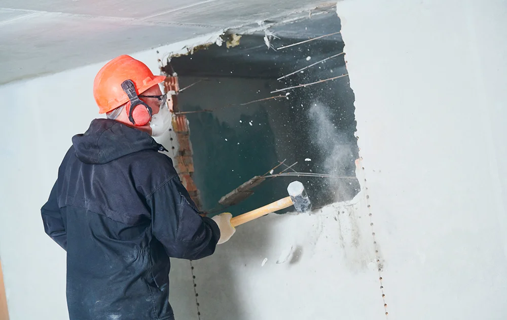 man hitting drywall with a hammer